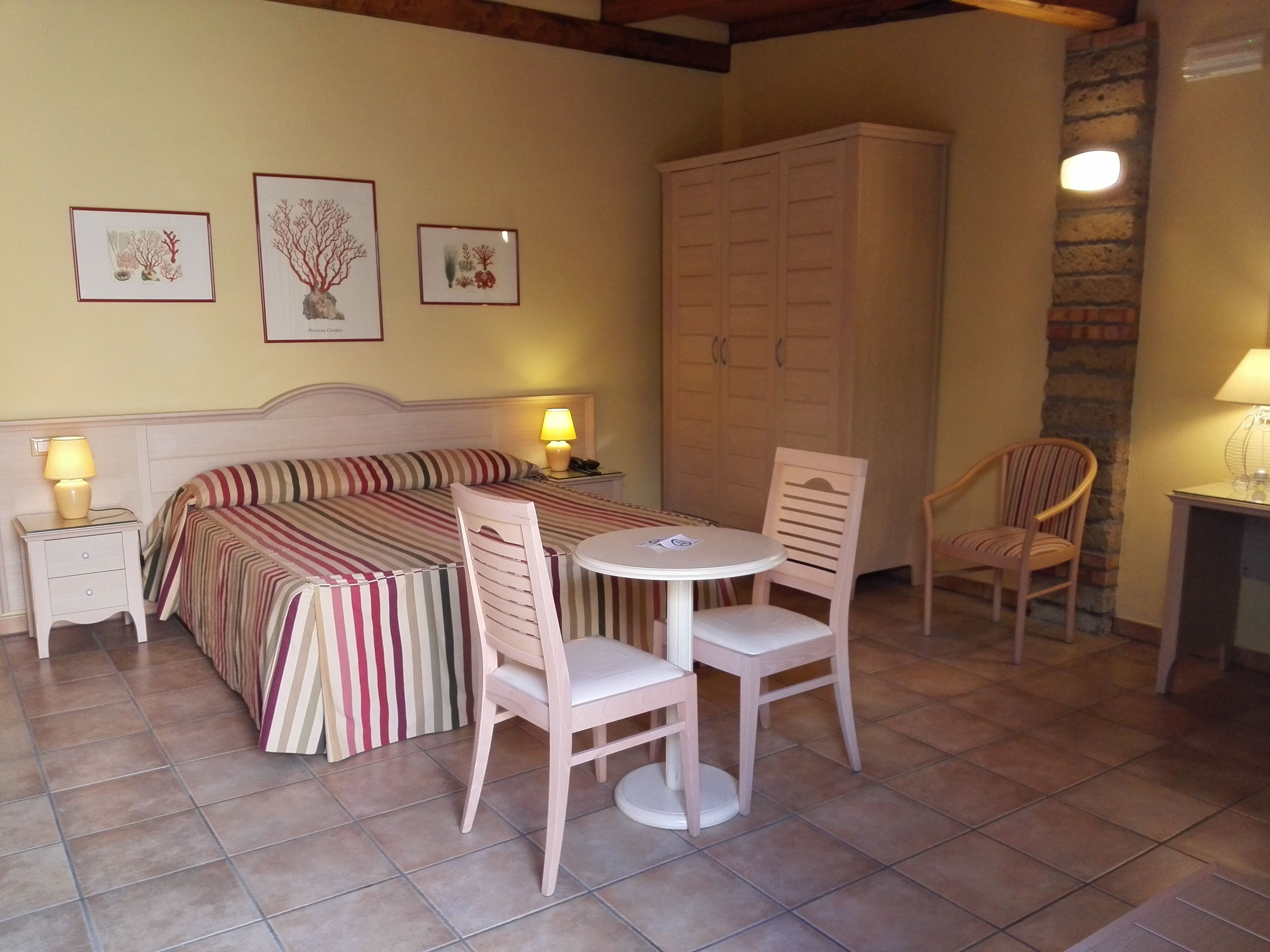 Une pièce confortable avec un lit, une petite table, deux chaises et un meuble.