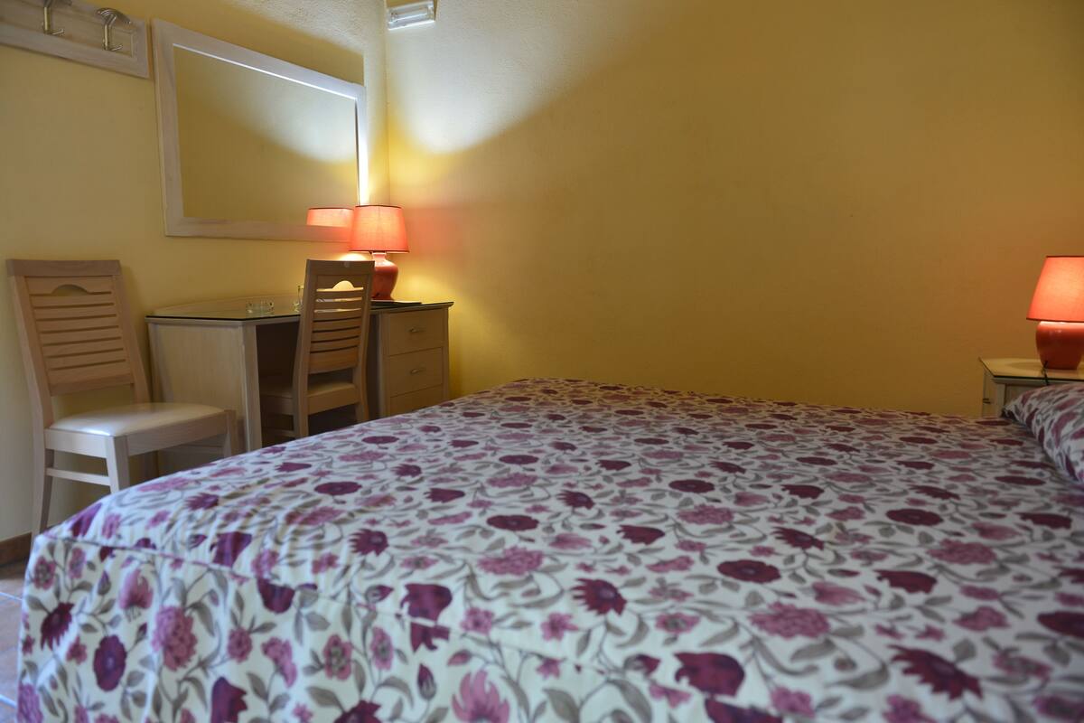 Una camera da letto con un letto, una scrivania, una sedia e due lampade.