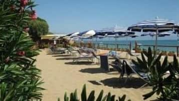 Een privéstrand, ligstoelen aan het strand, parasols, strandlakens