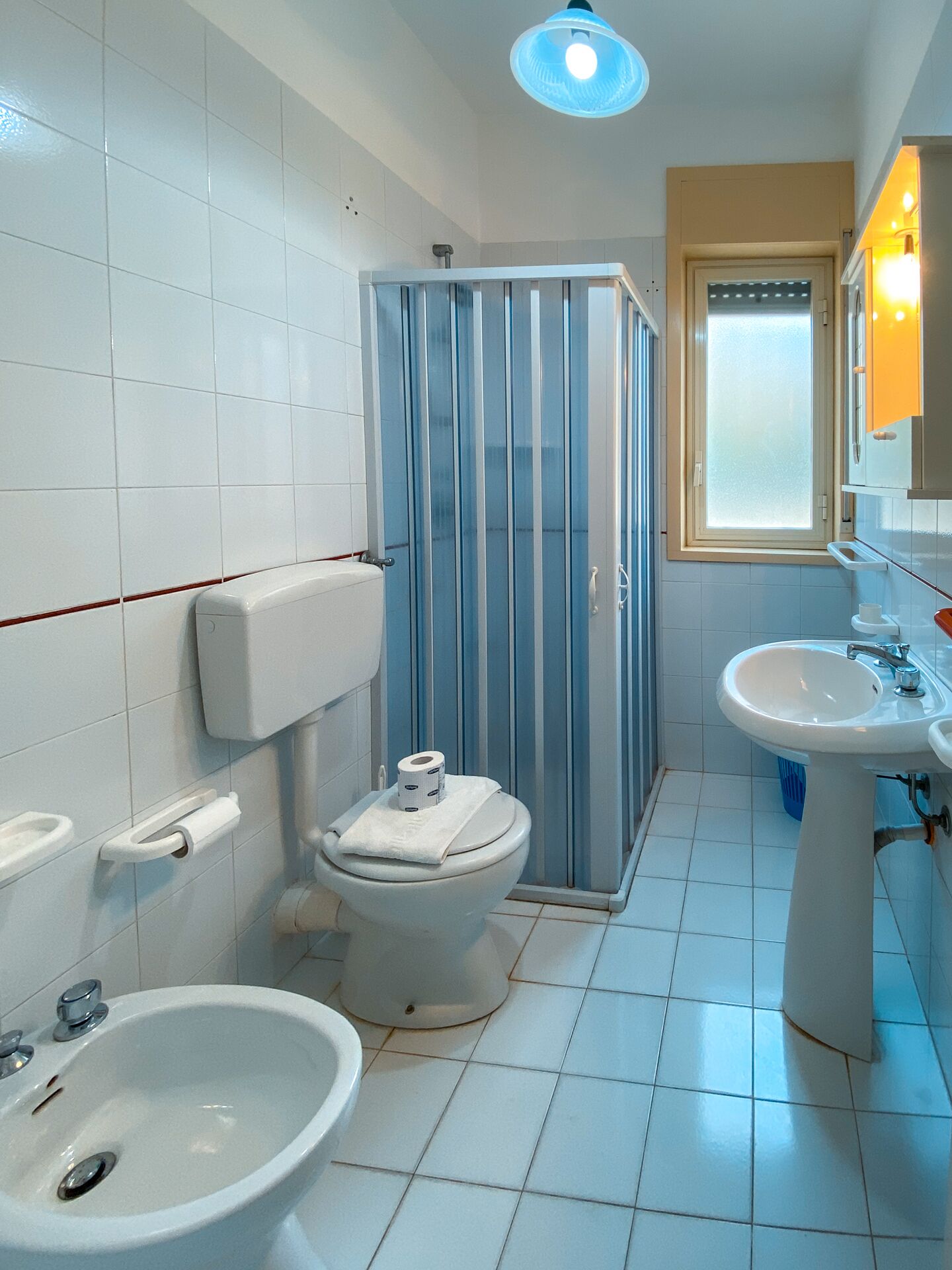 Un baño con inodoro, bidé, lavabo y cabina de ducha.