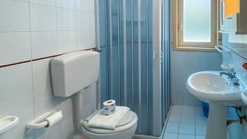 Un baño con inodoro, bidé, lavabo y cabina de ducha.