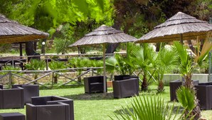 Buitenruimtes met rieten parasols, rieten meubels en potplanten.
