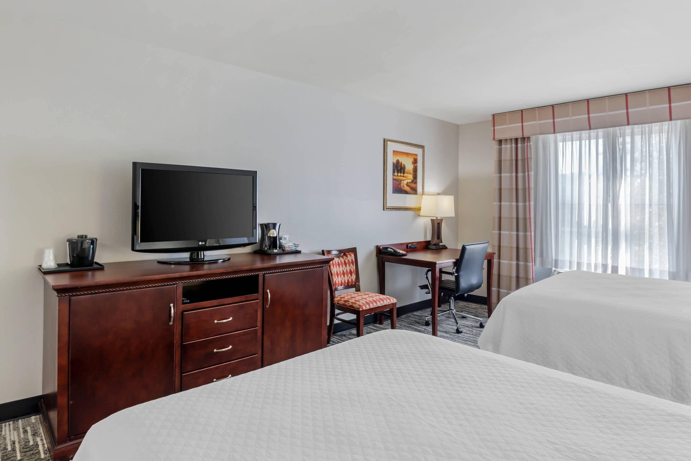 Une chambre d’hôtel comprenant un lit, un bureau avec un ordinateur, une télévision et une chaise.