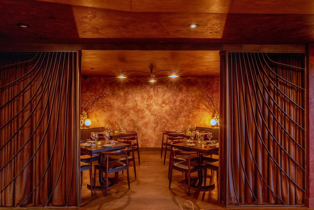 A restaurant with wooden walls and ceiling, dim lighting, and tables set for dining.