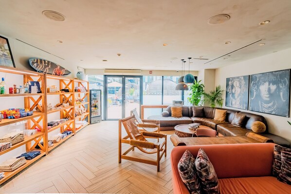 Amplia sala de estar con sofá, sillones y una mesa de centro. Hay estanterías de madera con varios objetos y un gran ventanal que ofrece vistas al exterior.