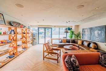 A bar area with sofas and round tables, a variety of bottles on shelves, and a view of buildings in the background. at CODA Williamsburg