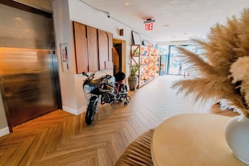 A modern living room with a grey sofa, wooden chairs, a dining table, and a kitchen area with a sink and cabinets. at CODA Williamsburg