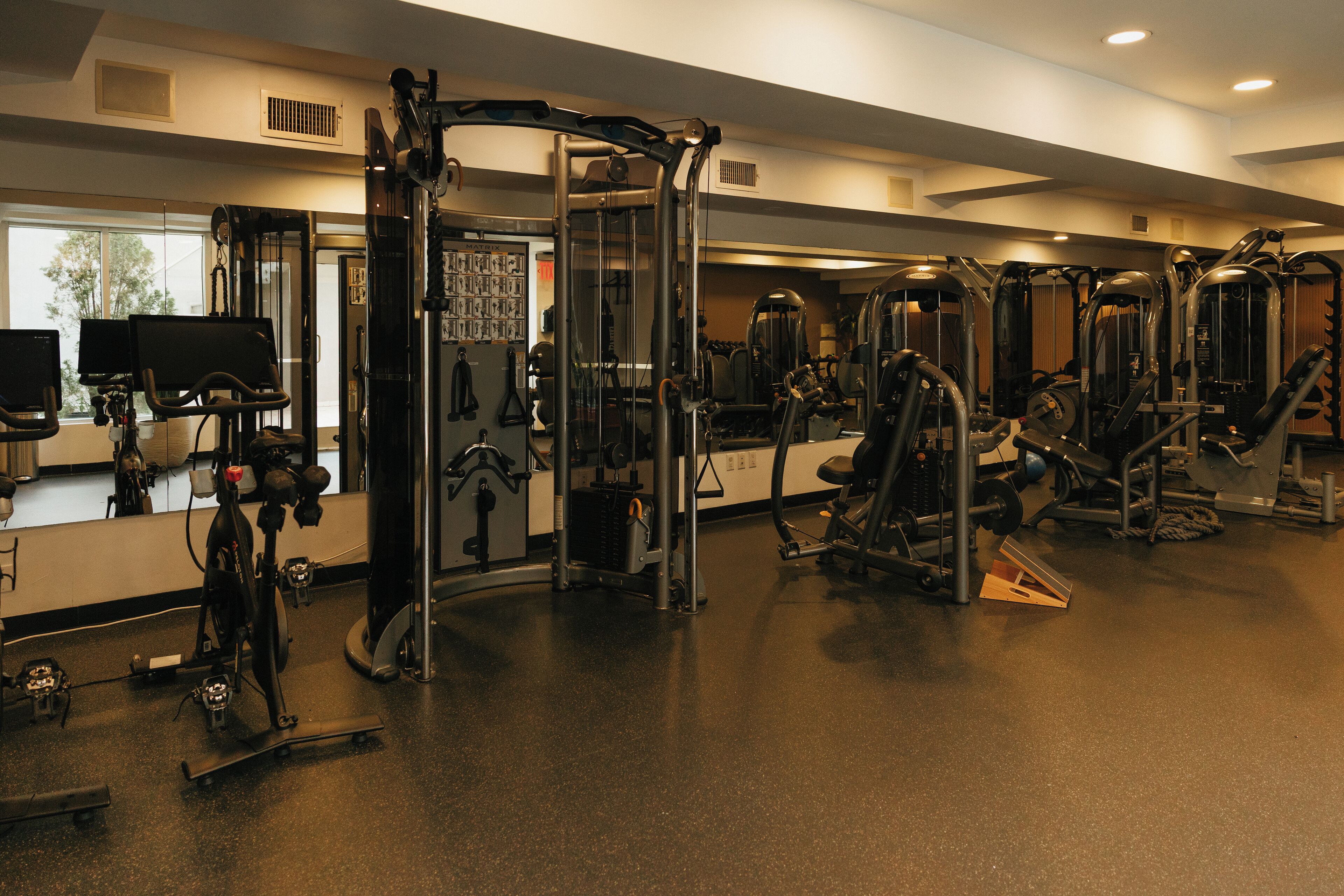 Ett gym med olika träningsmaskiner, en spegel och en TV som är monterad på väggen.