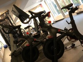 Una bicicleta estática Peloton en un gimnasio con otros equipos de ejercicio.