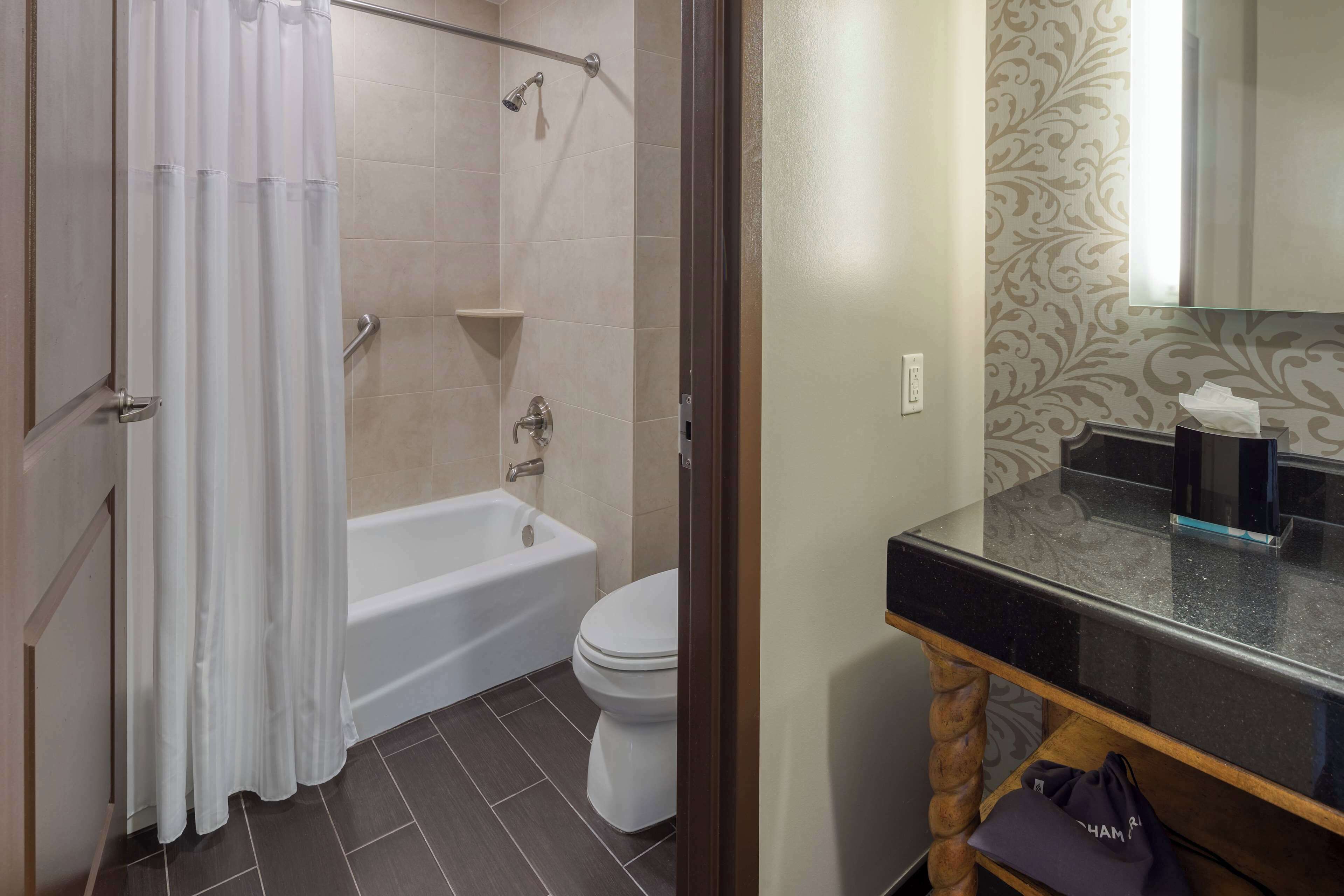 A bathroom with a bathtub, toilet, and a vanity with a mirror.