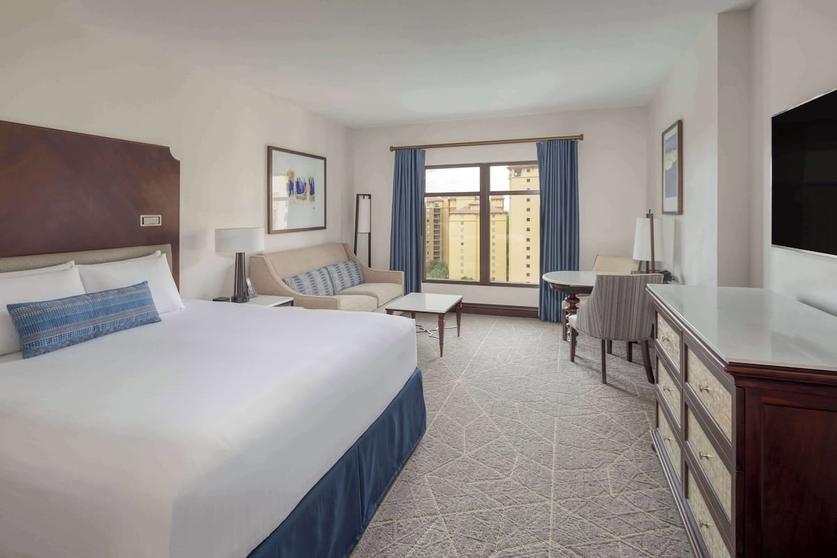 Een hotelkamer met een groot bed, een slaapbank, een bureau en een televisie.