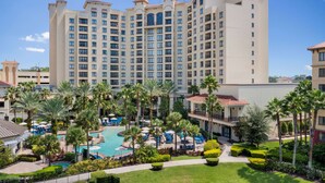 A hotel with multiple floors, a swimming pool, and palm trees. - Wyndham Grand Orlando Resort Bonnet Creek (Orlando)