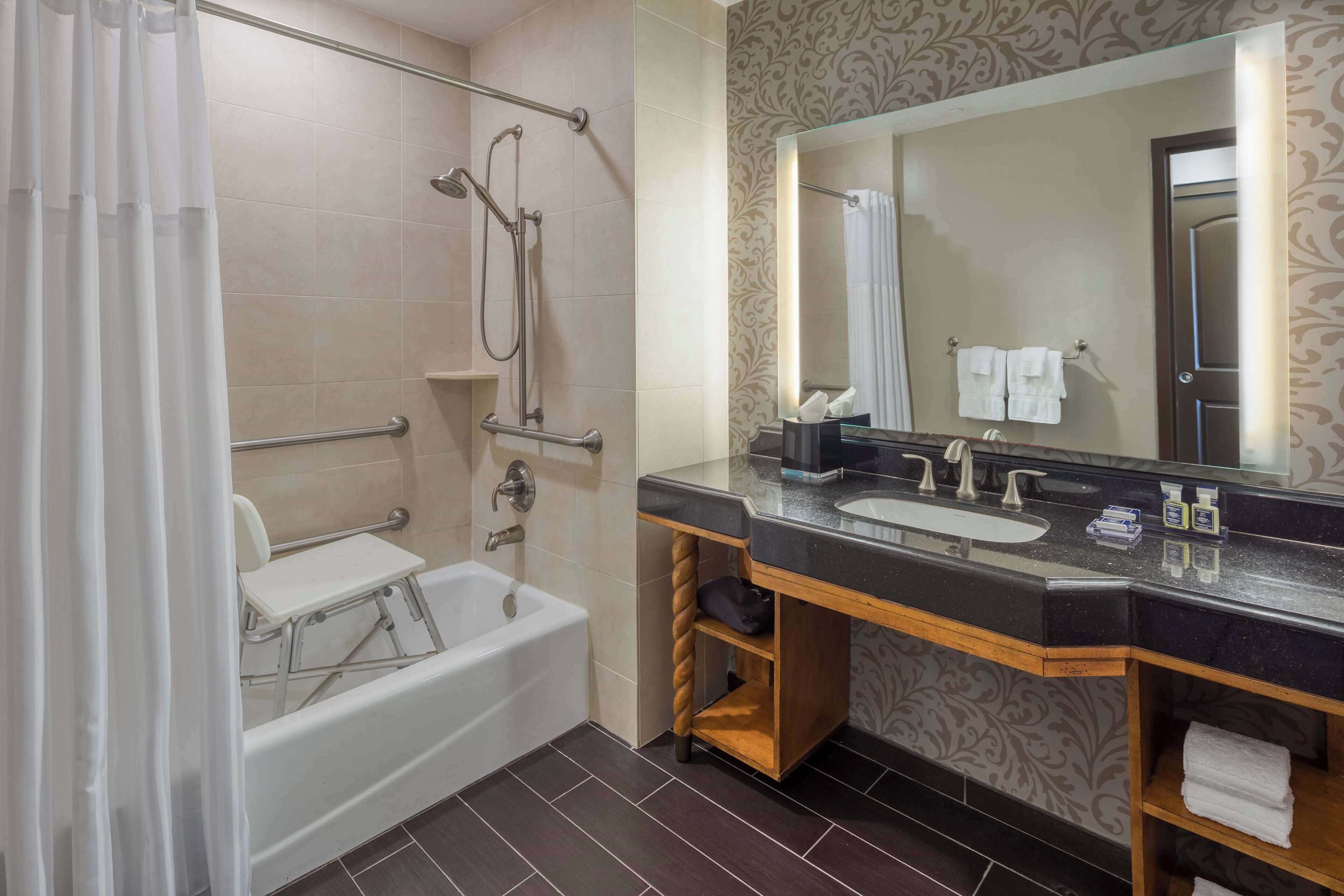 A modern bathroom with a bathtub, shower, vanity with a sink, and a large mirror.