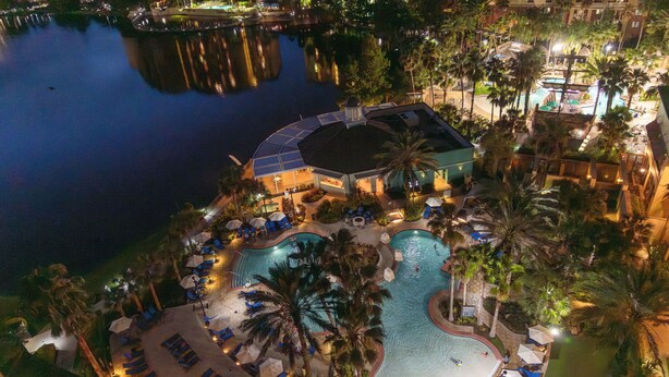 An aerial view of a resort with a large swimming pool surrounded by palm trees and lounge chairs. - Wyndham Grand Orlando Resort Bonnet Creek (Orlando)