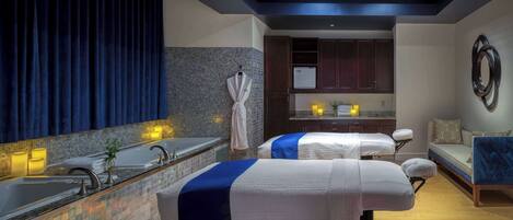 A spa room with a massage table, a sink, and a small kitchenette.