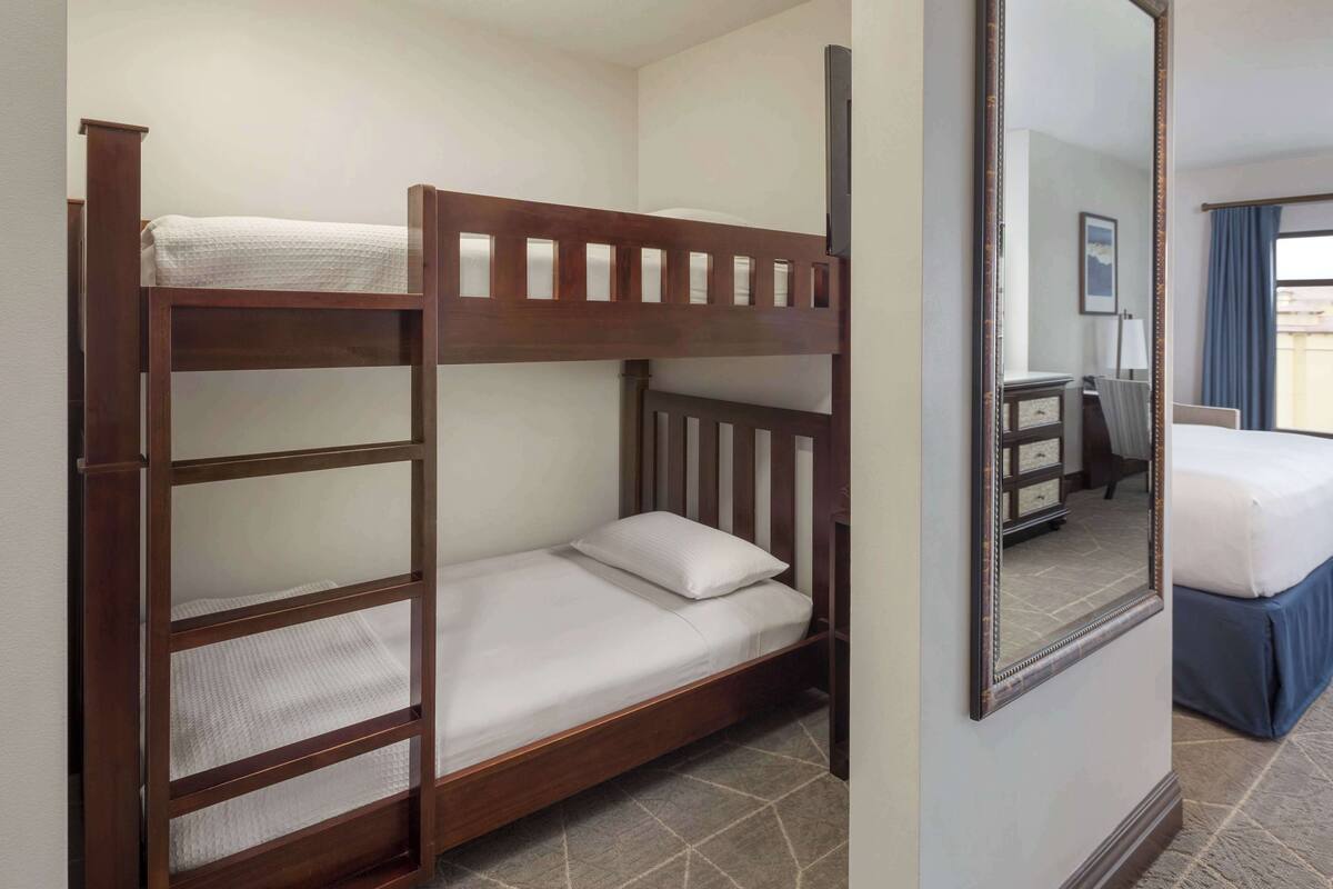 Een stapelbed met een spiegel, een bureau en een stoel in een hotelkamer.