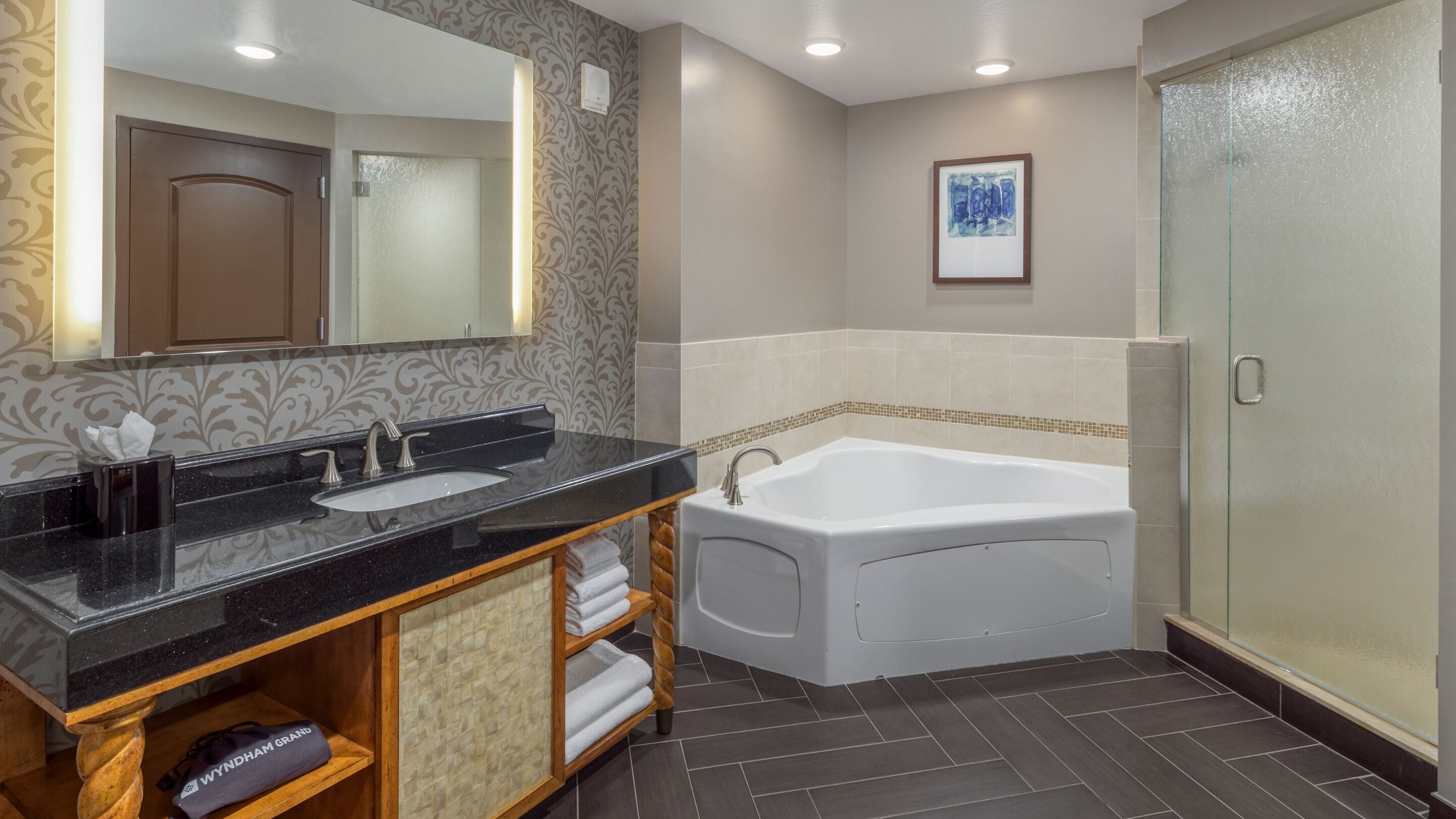 Une salle de bain moderne avec un plan de toilette noir, une baignoire blanche et une cabine de douche en verre.