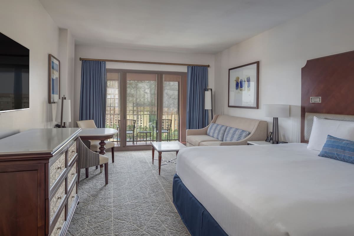 Hotelkamer met een bed, een bureau, een stoel, een klein tafeltje en uitzicht op buiten.