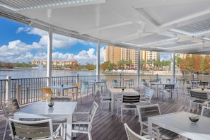 Relax on the patio with a view of the water and city skyline, surrounded by lush greenery and comfortable seating.