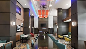 A hotel lobby with a long reception table, seating areas, and a large flat-screen TV.