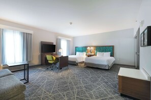 A hotel room with two beds, a desk, a chair, a TV, and a minibar.