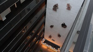 Un edificio de gran altura con varios pisos, un atrio central y una azotea con detalles decorativos.