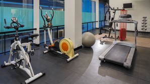 Un gimnasio con equipo de ejercicio, una cinta de correr y una pelota de ejercicio grande.