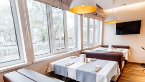 A hotel room with a large window, a flat-screen TV mounted on the wall, and a wooden floor. - Chagala Uralsk Hotel (Uralsk)