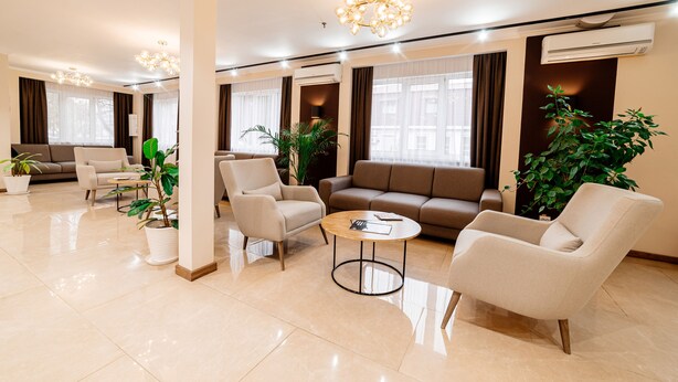 A modern living room with a sofa, armchairs, a coffee table, and potted plants. - Chagala Uralsk Hotel (Uralsk)