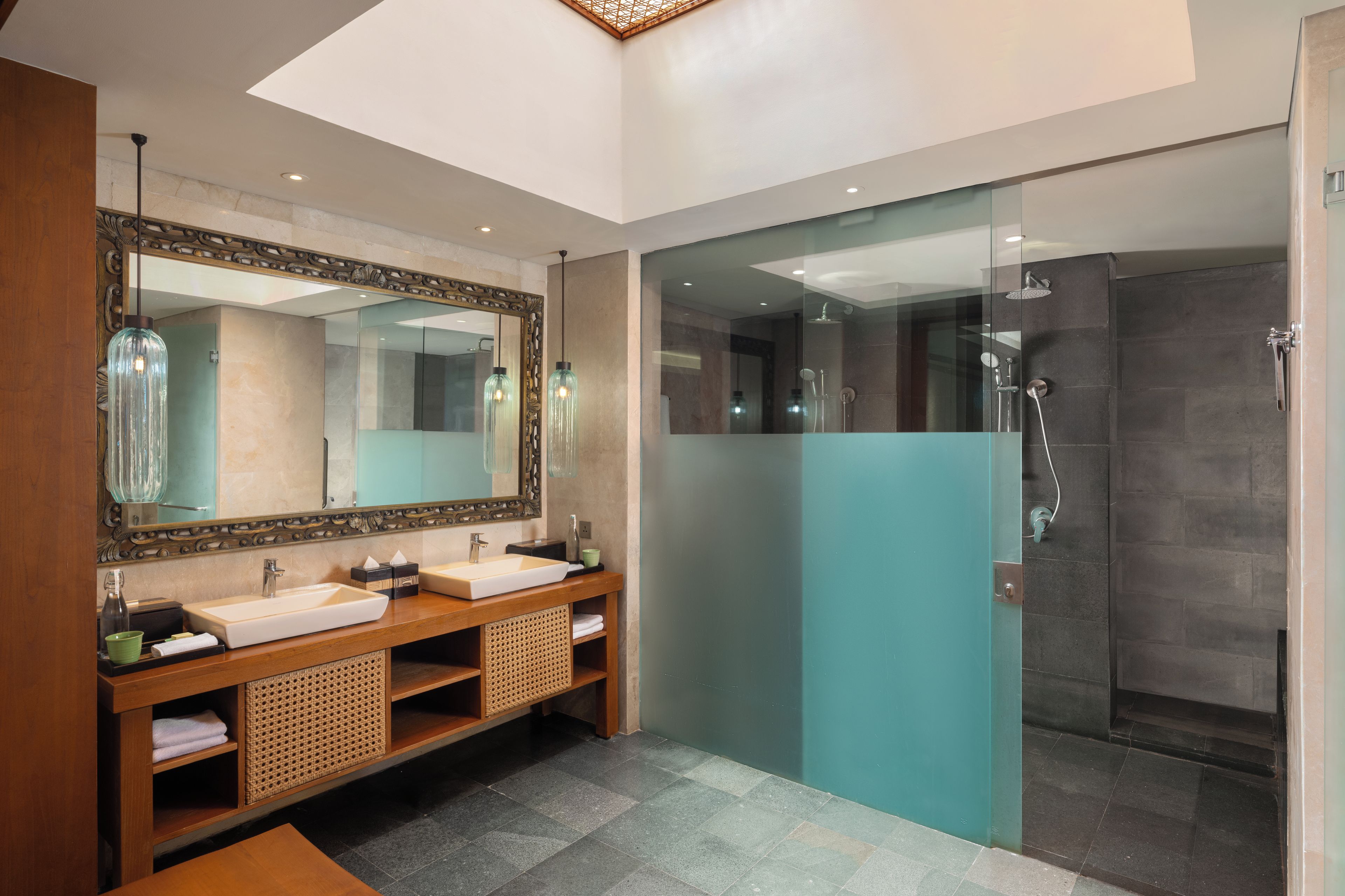 Ein modernes Badezimmer mit einem großen Spiegel, zwei Waschbecken, einer Dusche und einer Glasabtrennung.