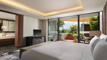 A modern hotel room with a large bed, a TV, a desk, and a view of a pool and garden.