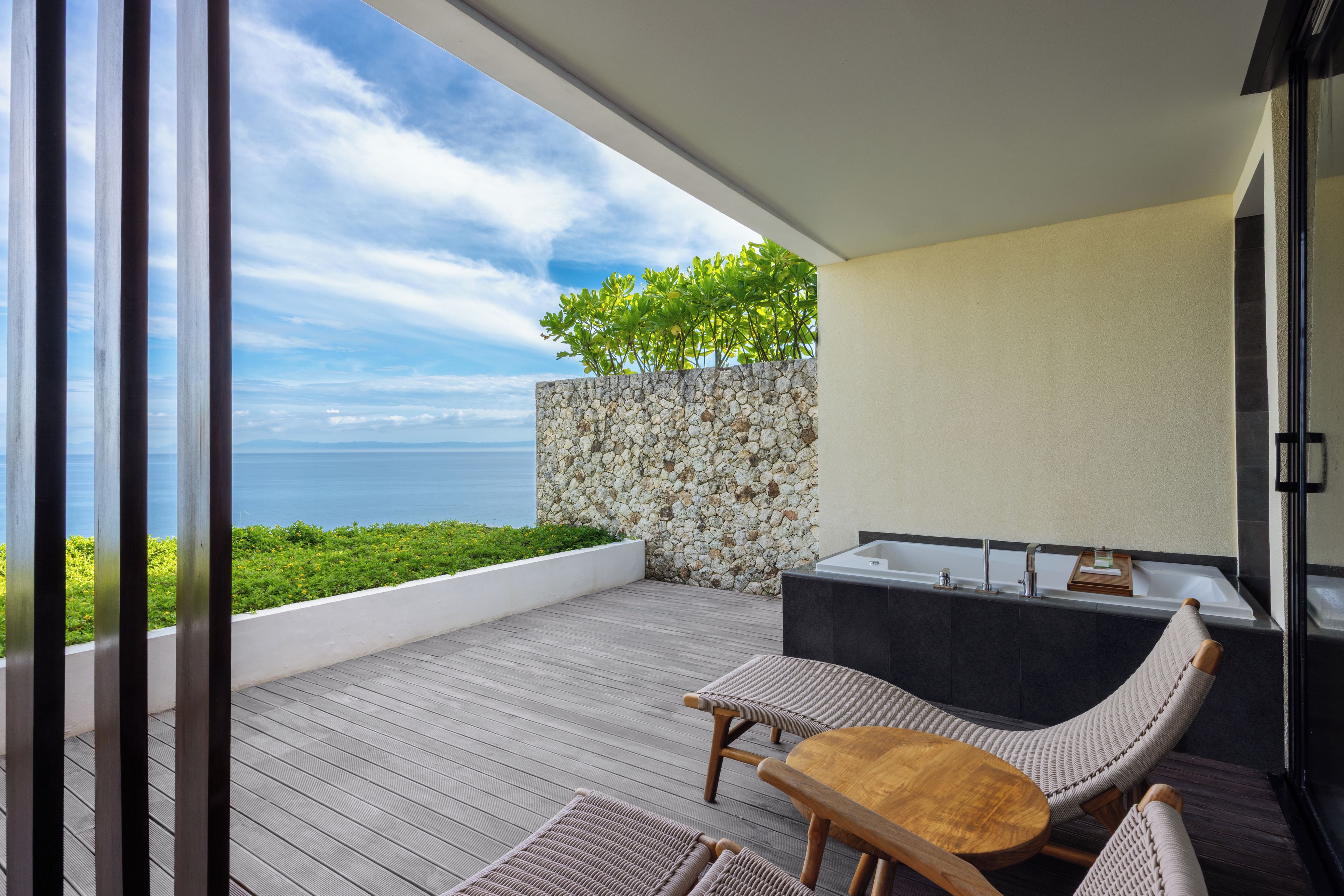 Ein Balkon mit Holzboden, Steinwand und Meerblick.