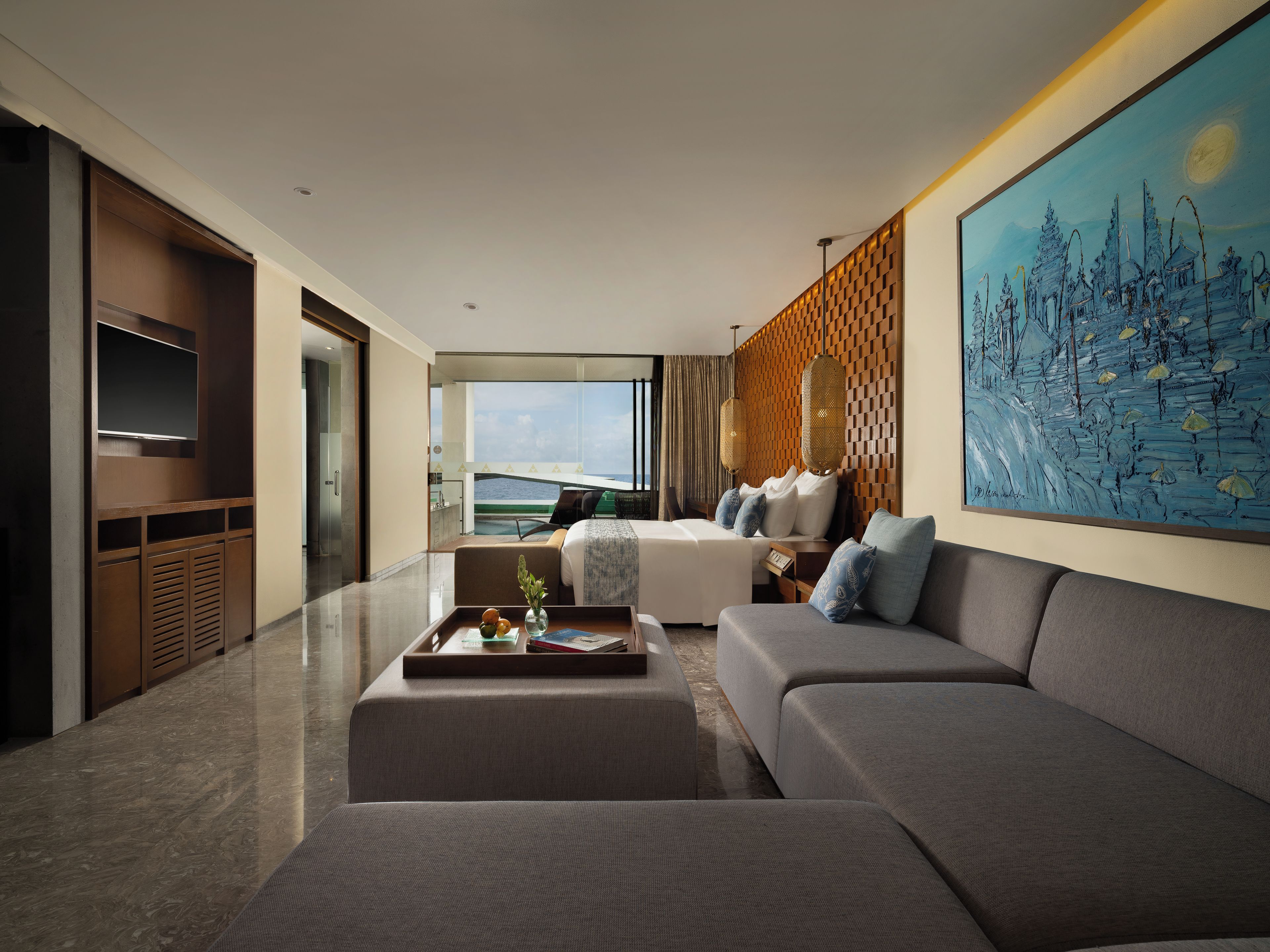 Une chambre d’hôtel moderne avec un grand lit, un canapé, une table basse et un tableau au mur.