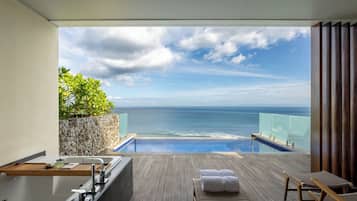 Varanda com vista para o oceano, deck de madeira, banheira e área de estar com toalhas.