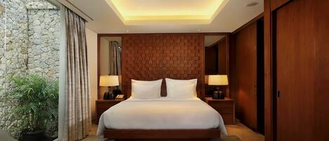 Un dormitorio moderno con una cama grande, cabecera de madera, lámparas de noche y una pared de piedra.