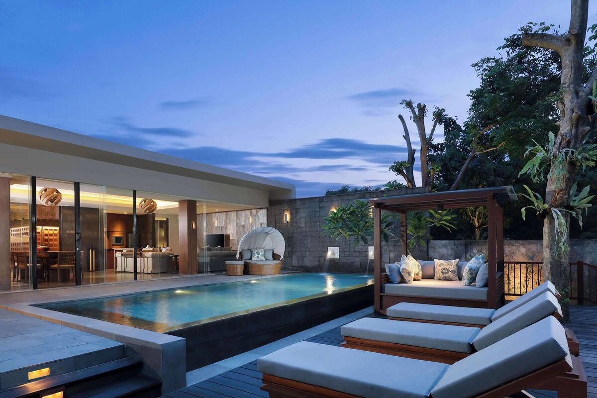 A modern outdoor pool area with lounge chairs and a covered seating area.