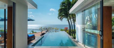 A modern infinity pool with a clear view of the ocean, surrounded by glass walls and wooden accents.