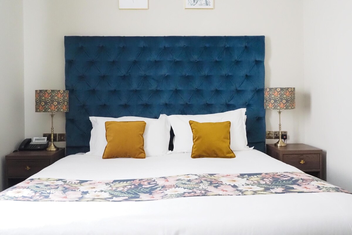 A bed with a tufted headboard, two bedside lamps, and a floral bedspread.