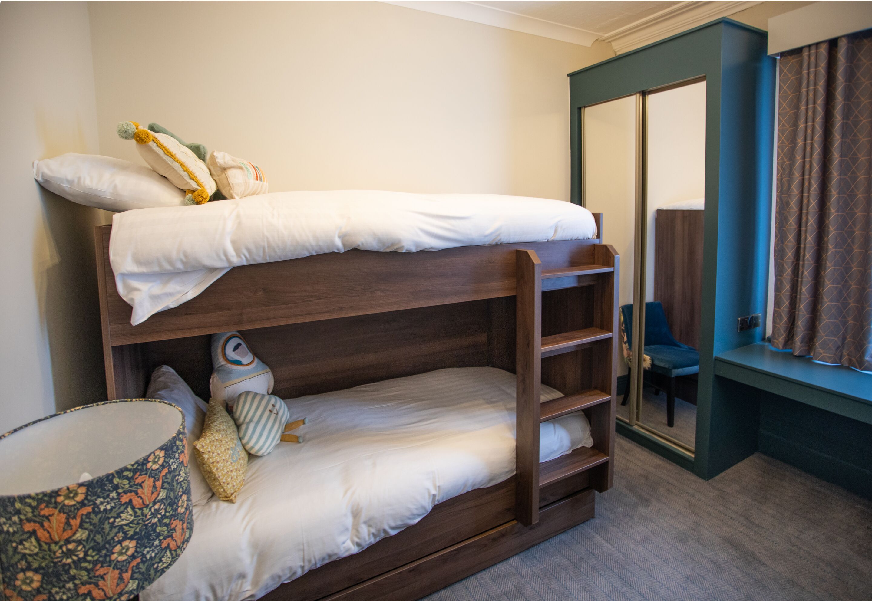 A bunk bed with a wooden frame, a small desk, and a chair.