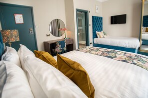 A hotel room with a large bed, a smaller bed, a TV, a mirror, a door, and a bathroom visible through an open door. - Hotel Collingwood, BW Signature Collection (Bournemouth)