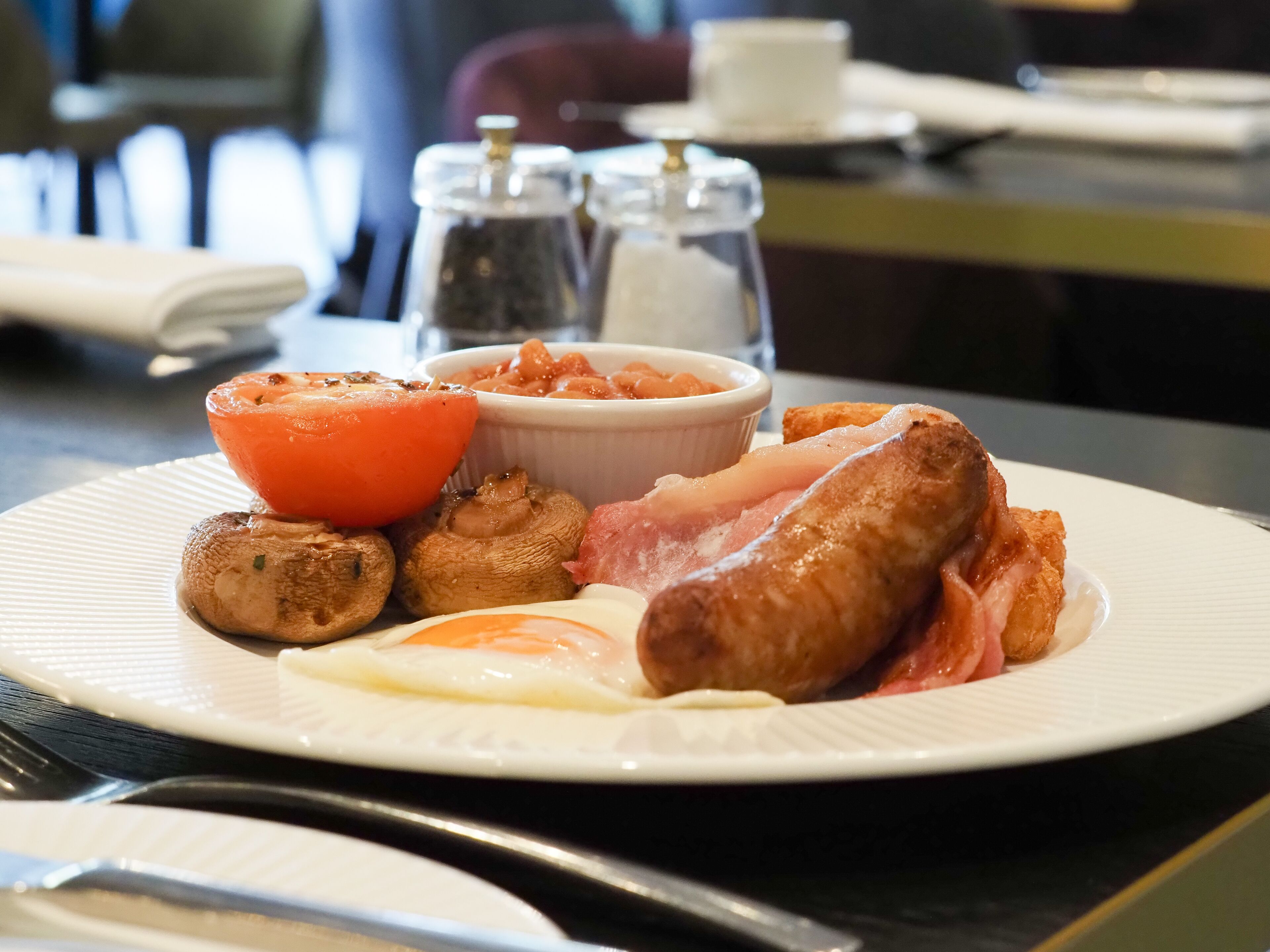 Un plato de comida para el desayuno con salchichas, huevos, champiñones y tomates.