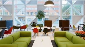 Un espacio interior moderno con sofás verdes, una mesa blanca y sillas coloridas.