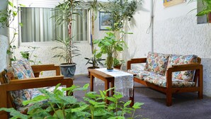 Une pièce chaleureuse avec un canapé en bois, une petite table et plusieurs plantes en pot.