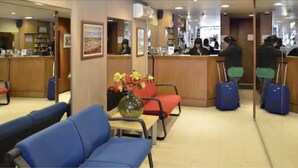 Un hall d’hôtel avec des sièges, un comptoir d’accueil et un vase rempli de fleurs.