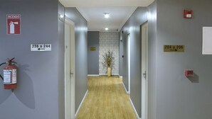 Un couloir avec des panneaux d’indication concernant la sécurité incendie, des portes numérotées et un extincteur.