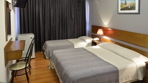 Une chambre d’hôtel avec deux lits, un bureau avec une chaise, un climatiseur et un tableau encadré au mur.