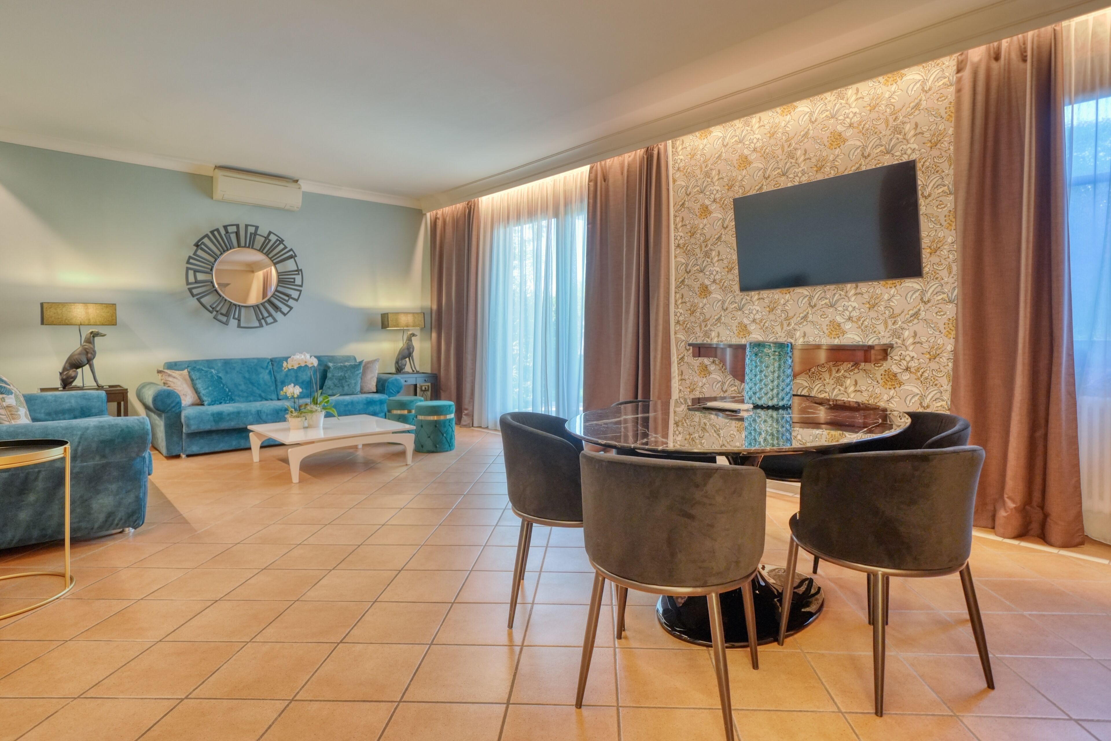 Ein modernes Wohnzimmer mit einem blauen Sofa, einem runden Glastisch und grauen Sesseln.
