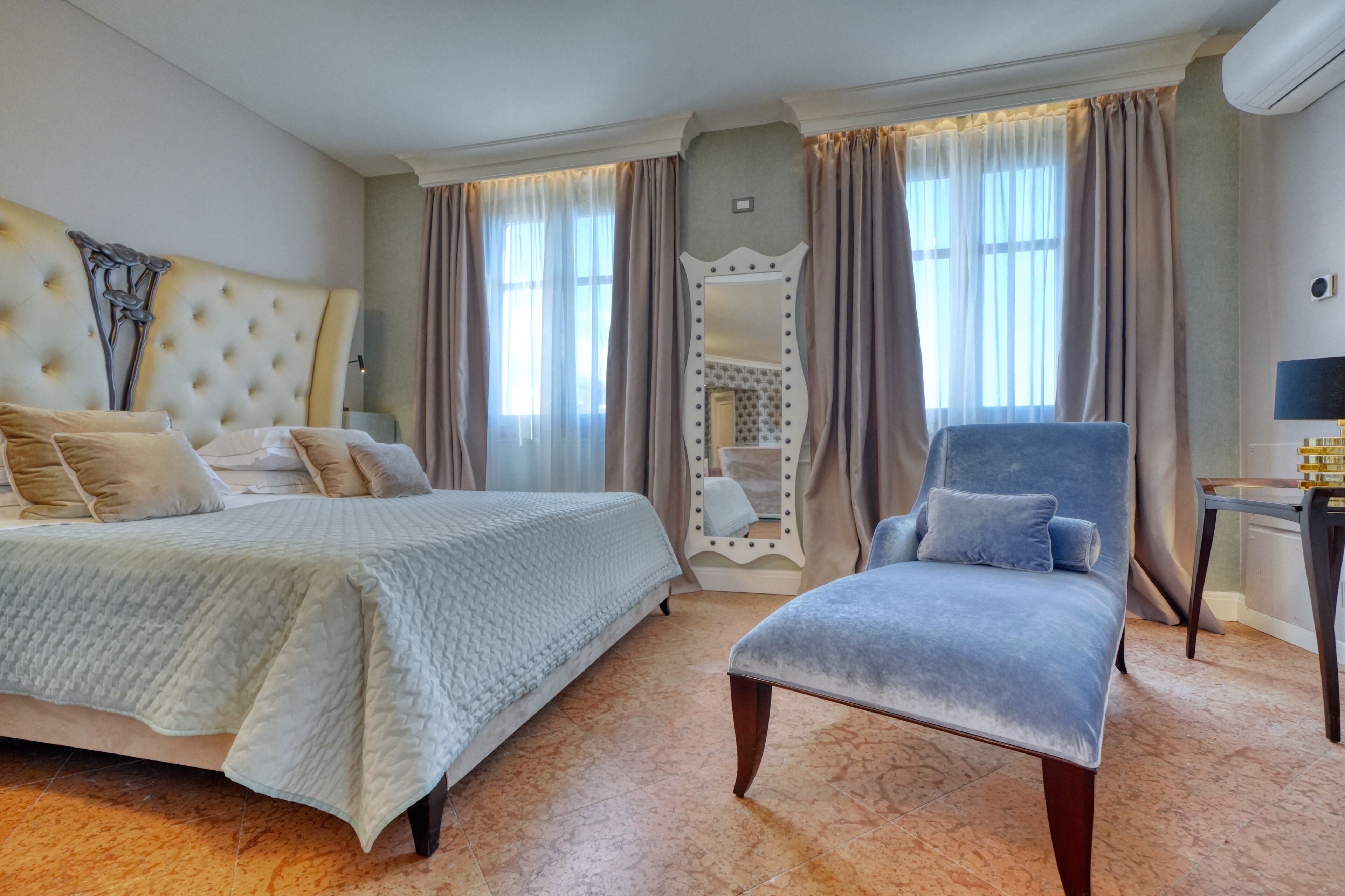A hotel room with a large bed, a vanity with a mirror, and a chair.