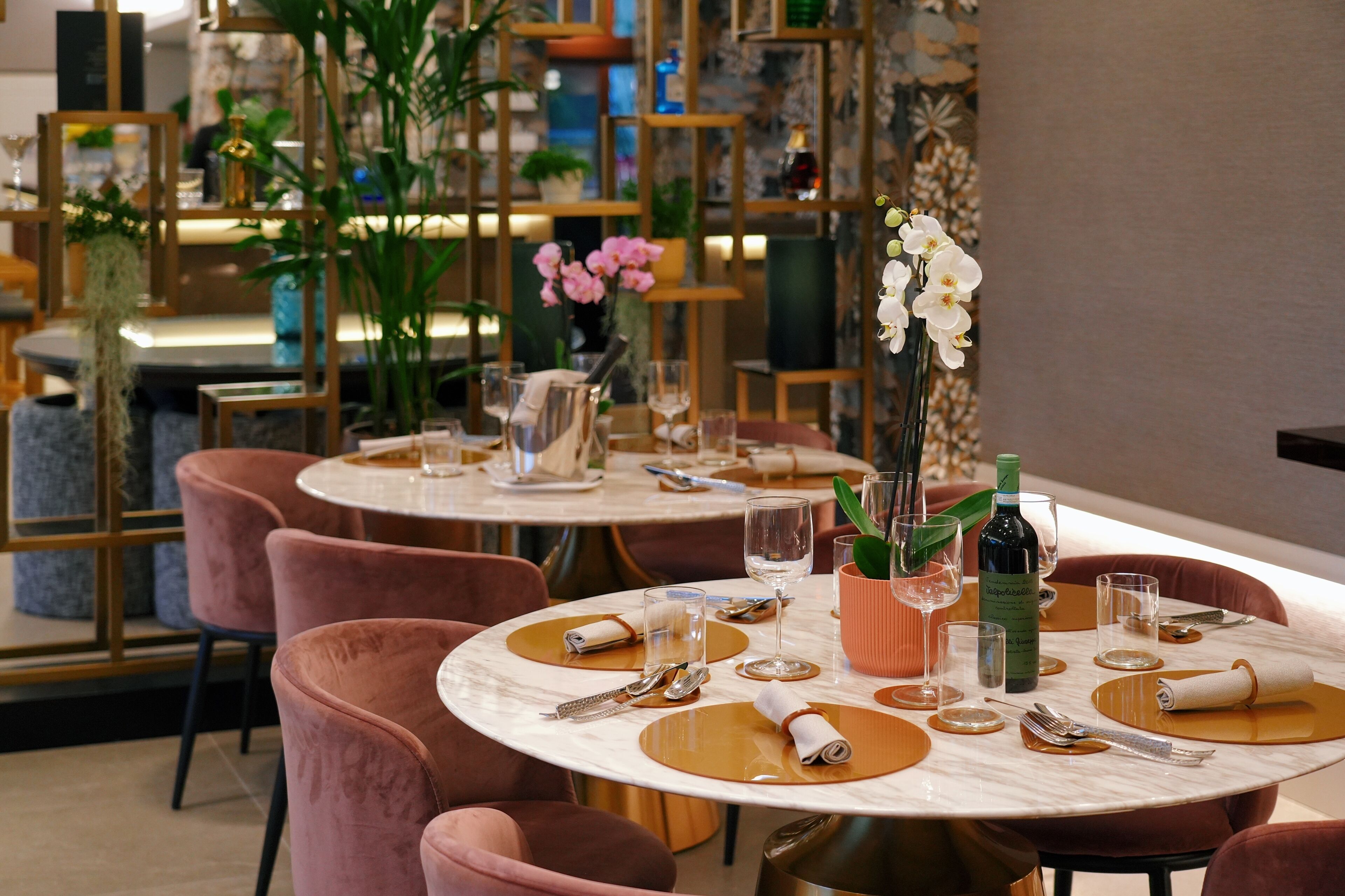 A restaurant with round tables, pink chairs, and a modern interior design.
