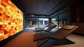 A modern indoor area with a brick wall, lounge chairs, and large windows.